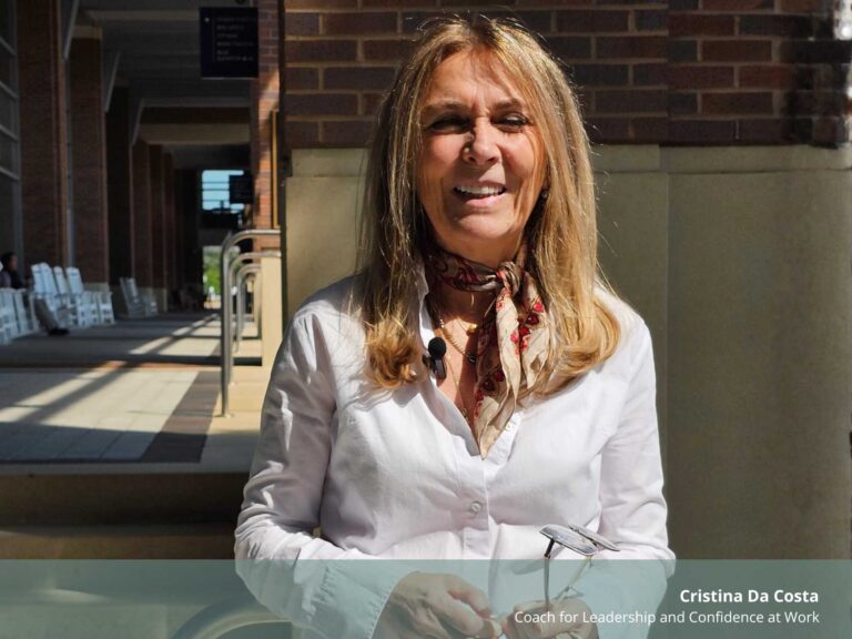 Retrato de Cristina Da Costa sorrindo ao ar livre. Ela é uma mulher de meia-idade, com cabelo loiro comprido, veste uma camisa branca e um lenço estampado ao pescoço. No canto inferior direito, lê-se o texto informativo com o seu nome e cargo profissional.
